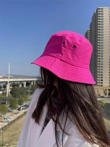 Close-up of a rose red bucket hat featuring breathable metal eyelets and washed cotton