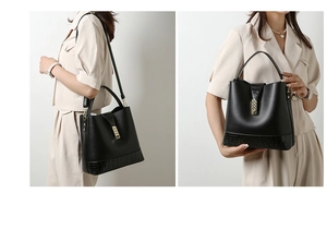 Detail of black leather bucket bag with crocodile texture base and gold metal buckle