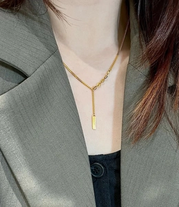 Close-up of 18K gold plated bar pendant necklace on model with elegant chain detail