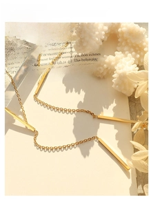 Detailed macro view of an 18K gold minimalist necklace with four slim geometric bar pendants