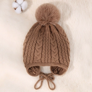 Detailed knit texture of camel winter hat with ear flaps and fluffy pom-pom
