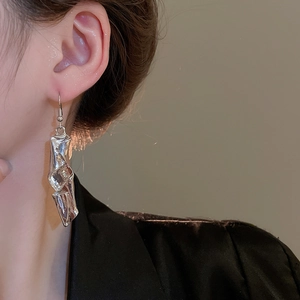 Close-up of irregular liquid metal twisted silver earring on model's ear profile