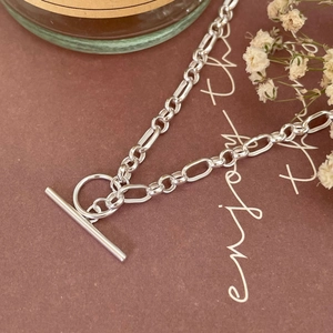 Detailed close-up of a silver 925 chain necklace with OT clasp and floral background