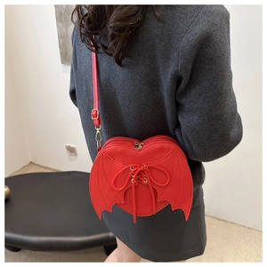 Detailed back view of a red heart-shaped bag with black bat wings on a model