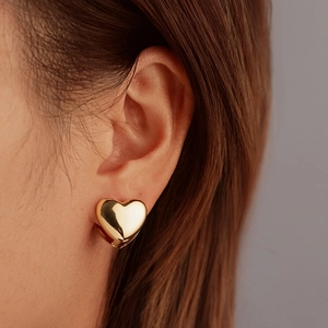 Polished gold heart-shaped earrings for women shown worn on a model in a minimalist style