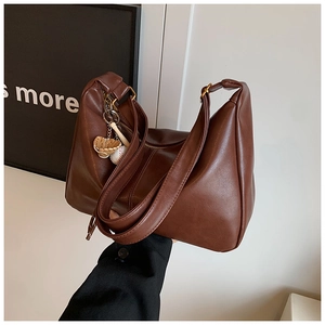 Detailed side view of deep brown PU leather tote bag with baseball glove pendant detail