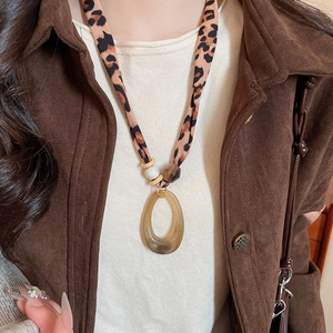 Detail of bohemian necklace featuring leopard print fabric, amber resin and wooden beads