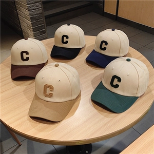 Detailed overhead view of two-tone baseball caps featuring a large letter C embroidery