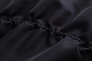 Detailaufnahme der elastischen Faltennaht am Ärmel der schwarzen Bomberjacke