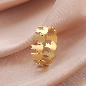 Macro shot of gold stainless steel bird silhouette ring on silk fabric background