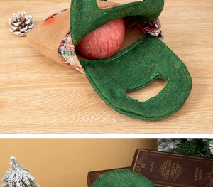 Close-up of green felt Christmas gift bag with red plaid handle holding a fresh apple