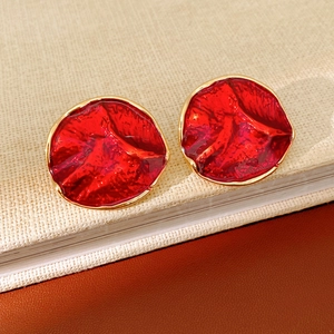 Close-up of red enamel earrings with gold edges on a vintage book surface