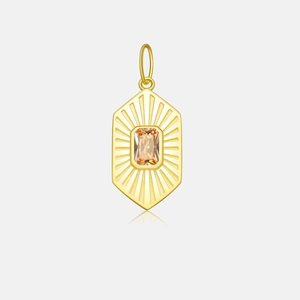 Macro detail of gold hexagon pendant with orange gem and radial engraved lines