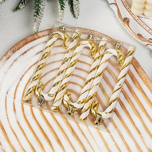 Set of 6 gold and white spiral candy cane ornaments on snow-covered wooden tray