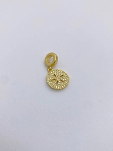 Close-up of golden disk pendant with hollow flower pattern and pavé cubic zirconia
