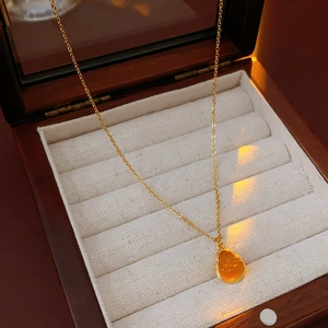 Detailed close-up of a gold-plated Buddha pendant necklace in a wooden jewelry box