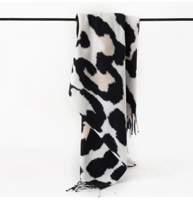 Detail of soft black and white cow print scarf with decorative fringe tassels