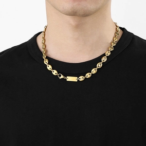 Detail view of a gold pig nose chain necklace with a small rectangular tag on a model