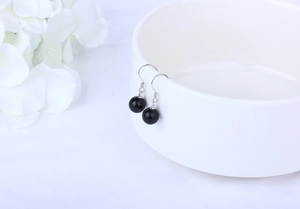 Detailed close-up of minimalist black agate bead earrings with elegant silver hooks