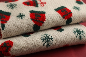 Close-up of beige Christmas knit fabric with red stockings and green snowflakes patterns