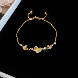 Detailed view of gold heart slider bracelet with LOVE engraving and pavé zircon stones