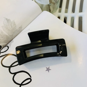 Glossy black rectangular hair claw clip for women shown on a minimalist magazine backdrop