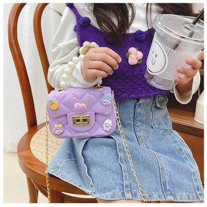 Close-up of girls purple quilted crossbody bag with golden chain and cartoon charms