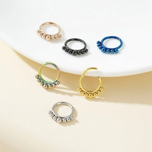 Detail view of colorful stainless steel septum rings in six metallic colors on cream background
