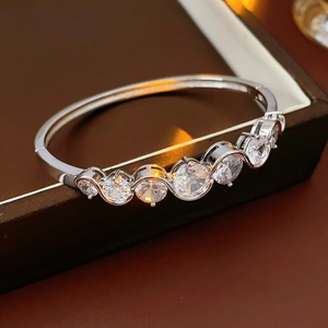 Close-up of sparkling round zircon stones inlaid on a silver wave-shaped bangle