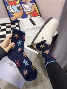 Detail of dark blue cotton socks with colorful floral patterns and white slippers