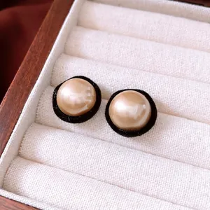 Elegant vintage faux pearl stud earrings with black flocking trim on a jewelry box display