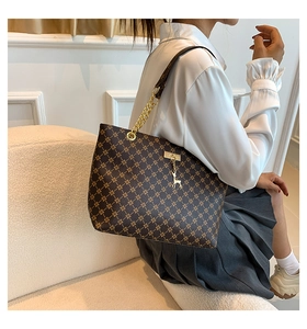 Detail of vintage brown tote bag with geometric pattern and metal chain strap decoration