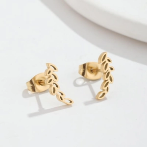 Macro detail of gold leaf-shaped stud earrings with intricate cutout wheat grain patterns