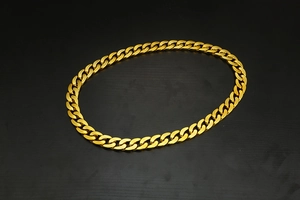 Detailed top view of gold-tone chunky cuban link chain on a sleek black background