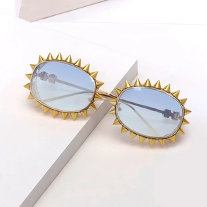 Detailansicht goldener Punk-Sonnenbrille mit blauen Gläsern und spitzen Nieten-Details