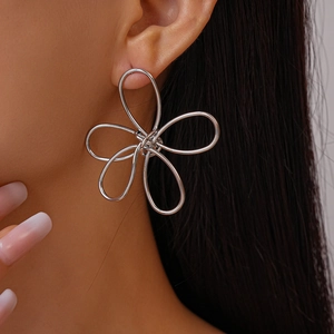Close-up of minimalist silver hollow flower earrings worn by a model in a profile view
