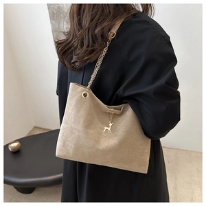 Model mit beiger Wildleder-Einkaufstasche mit Goldkette und Hirsch-Anhänger