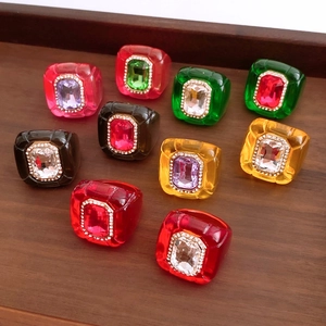 Detail of vintage hexagonal resin rings set with rhinestones on a dark wood tray
