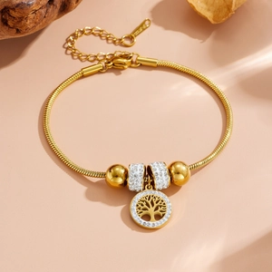Détail d'un bracelet en acier inoxydable doré avec pendentif Arbre de Vie et strass blancs