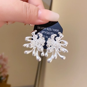 Detail of 925 silver flower earrings featuring white pearls and diamond accents on black card