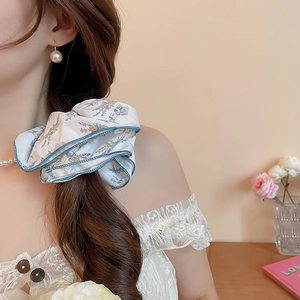 Detail of floral scrunchie with blue scalloped edges and delicate fabric texture