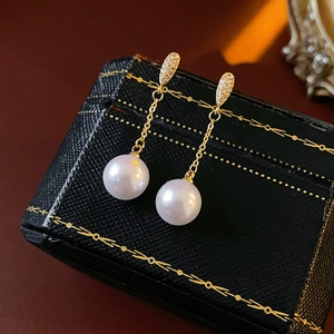 Detailed view of pearl earrings with gold-plated studs and sparkling zircon accents