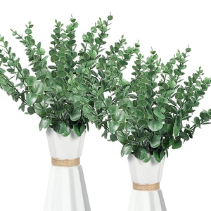 Two artificial green eucalyptus plants in white geometric vases with twine details