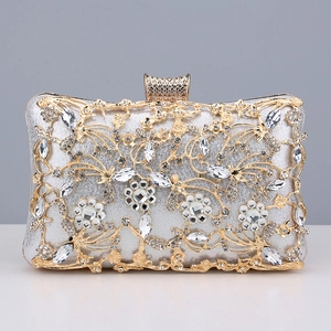 Close-up of silver evening clutch featuring intricate gold floral hollow patterns and rhinestones