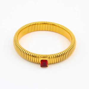 Macro detail of gold-plated ribbed bangle with a rectangular red zircon stone setting