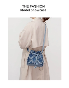 Detail of blue denim patchwork bucket bag with fringe edges and leather drawstring