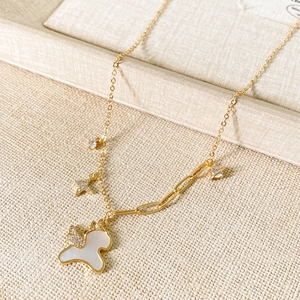 Detail of gold necklace featuring zircon star charms and mop horse pendant on textured fabric