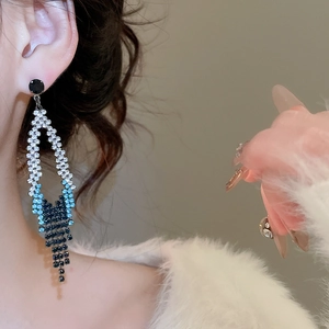 Détail macro de boucles d'oreilles à pompon avec strass dégradé bleu et aiguille en argent