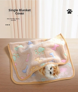 Close-up of soft coral fleece pet blanket with colorful paw and bone prints