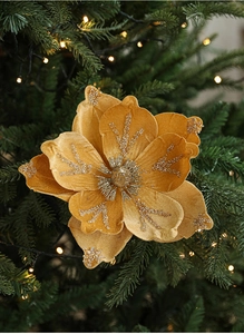 Macro shot of 24cm golden velvet Christmas flower with glitter on a lit tree